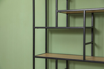Empty wooden shelving unit near olive wall indoors
