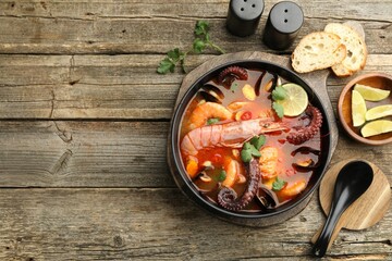 Delicious seafood soup served on wooden table, flat lay. Space for text