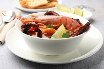 Tasty seafood soup served on light grey table, closeup