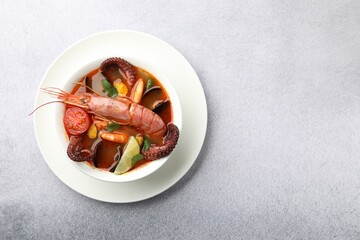 Tasty seafood soup in bowl on light grey table, top view. Space for text