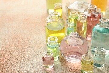 Perfume bottles with aromatic oils on beige textured background, closeup. Space for text
