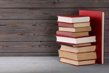 Stack of old books on grey wooden table, space for text