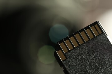 One SD memory card on blurred background, closeup. Space for text