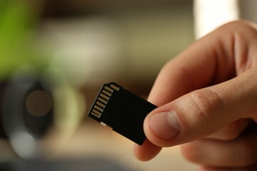 Man with SD memory card on blurred background, closeup