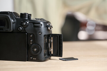 SD memory card and photo camera on wooden table, closeup. Space for text