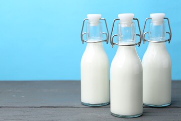 Fresh milk on wooden table against light blue background. Space for text
