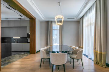 The interior of a country house with an elegant dining area with a wide passage into the kitchen...