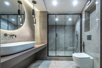 The bathroom is decorated in a modern style, with elegant plumbing, elegant marble tiles and a...