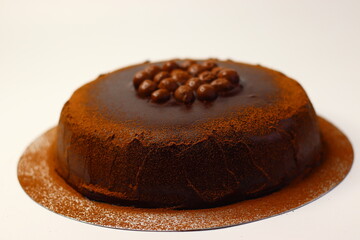 Rich chocolate cake topped with crunchy chocolate coated nuts, dusted with cocoa powder