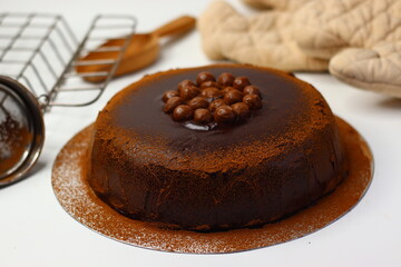 Rich chocolate cake topped with crunchy chocolate coated nuts, dusted with cocoa powder