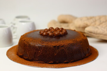 Rich chocolate cake topped with crunchy chocolate coated nuts, dusted with cocoa powder