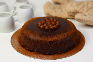 Rich chocolate cake topped with crunchy chocolate coated nuts, dusted with cocoa powder
