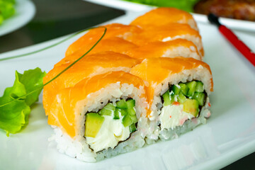 Sushi rolls with fresh salmon and vegetables on white plate