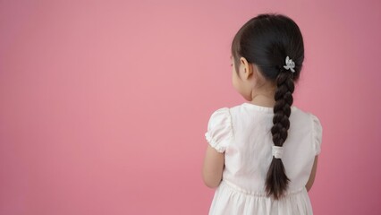 Young girl with braided hair posing for the camera. Her back is turned to view her braid.