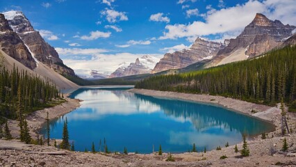 Vivid blue alpine lake amidst dense forests of the Canadian Rocky Mountains. Picture taken on a clear day.