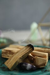 Smoldering palo santo stick and gemstone on table, closeup