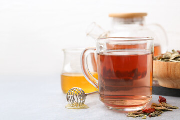 Delicious herbal tea with honey and dry leaves on grey table, closeup. Space for text