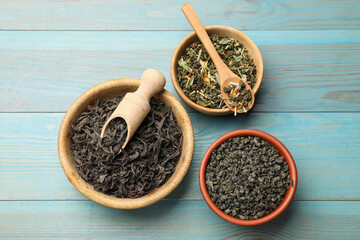 Different dry tea leaves in bowls on light blue wooden table, flat lay