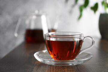 Freshly brewed tea in glass cup on wooden table, closeup