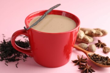 Aromatic Masala tea in cup, dry leaves and spices on pink background, closeup