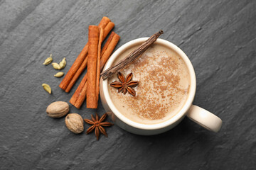 Aromatic Masala tea in cup and spices on black table, flat lay
