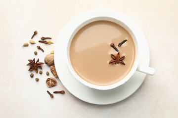 Aromatic Masala tea in cup, dry leaves and spices on light grey table, flat lay