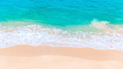 Aerial view of a peaceful tropical coastline with clear turquoise waves and white sand.