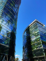 Modern skyscrapers and lush trees against blue sky, double exposure. Low angle view