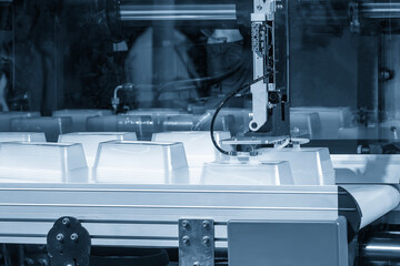 Close up scene material handling process the food container by robotic system from injection...