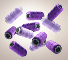 Many sewing threads in different shades of purple flying on beige grey gradient background