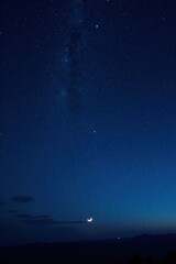 Fototapeta premium Dark vastness of starry night sky with numerous twinkling stars and a bright crescent moon hanging low in the distance , celestial bodies, black sky, galaxy