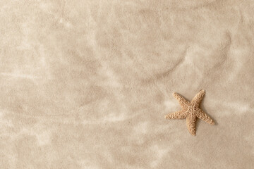 Sandy beach with beige starfish as natural textured background for summer travel and vacation design