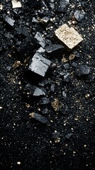 Gold cube sits among irregular dark mineral chunks on a grainy, textured base