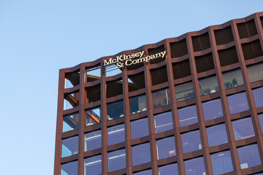 Poznan, Poland - March 15, 2025: Modern office building with McKinsey & Company logo on top floor facade, featuring large glass windows and geometric design under clear blue sky
