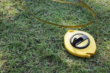 Yellow Measuring Tape on grass Background &ndash; Precision Tool Isolated High-Quality