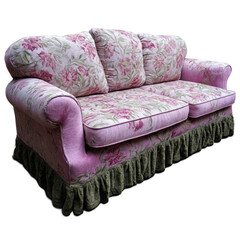 A vintage floral patterned sofa with pink and green hues and a ruffled skirt, resting on a neutral background