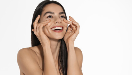 Natural beauty and real emotions. Beautiful woman laughing, touches her face, excitement from radiant skin, fresh look after beauty treatment in spa salon, looking up and smiling, white background © Liubov Levytska