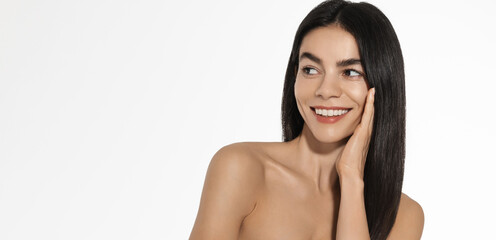 Beauty, head and shoulders portrait. Beautiful woman touches her face, looks at white blank space with interest and pleased smile, advert of skincare, haircare treatment, beauty salon promotion © Liubov Levytska