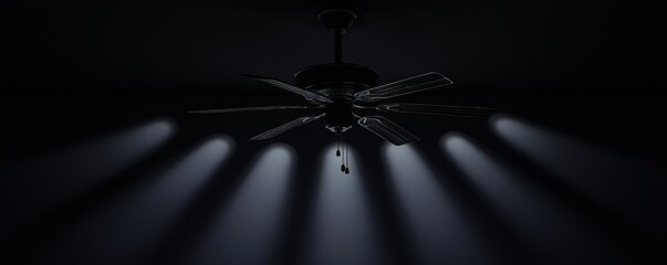 A ceiling fan casts shadows in a dimly lit room.
