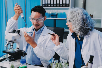 Team Asian scientists in a lab conducting food research using a microscope and lab equipment,...