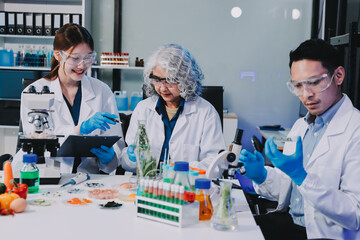 Team Asian scientists in a lab conducting food research using a microscope and lab equipment,...