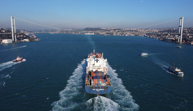 Istanbul, Turkey - January 14, 2022: Aerial view of a CMA CGM container ship sailing through Bosporus strait. A tugboat is seen on the left.