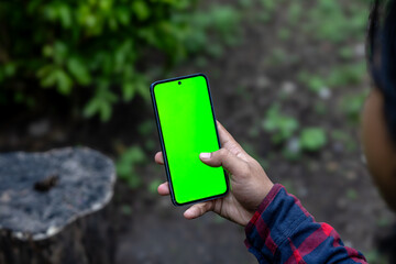 Man Scrolling Social Media on Smartphone with Green Screen. Hands Using Smartphone for Social Media. Scrolling Through Social Media on Mobile Device