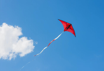 A red kite is flying high in the sky