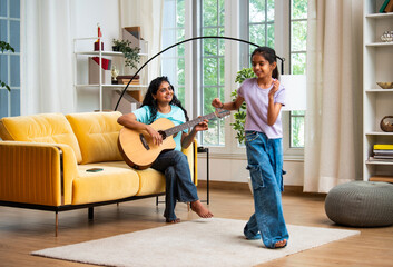 Asian mother and daughter enjoy music time together, dancing and playing guitar at home