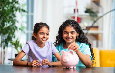 Mother and daughter save money at home, placing coins in piggy bank to build good financial habits