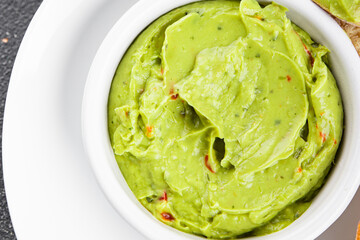 Guacamole dip avocado sauce cold appetizer vegetables dish organic fresh tasty gourmet food background on the table rustic food top view copy space keto and paleo diet vegetarian and vegan food