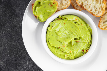 Guacamole dip avocado sauce cold appetizer vegetables dish organic fresh tasty gourmet food background on the table rustic food top view copy space keto and paleo diet vegetarian and vegan food