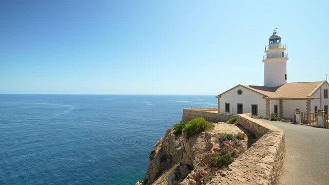 White capdepera lighthouse standing on a cliff overlooking the blue mediterranean sea in mallorca, balearic islands, spain