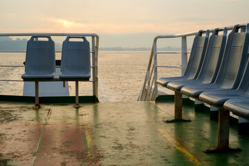 View from the ferry boat deck. Empty passenger seats, rusty surfaces, cloudy weather and the straits of the Hellespont (Dardanelles) in the background compose a unique marine landscape. Turkey.